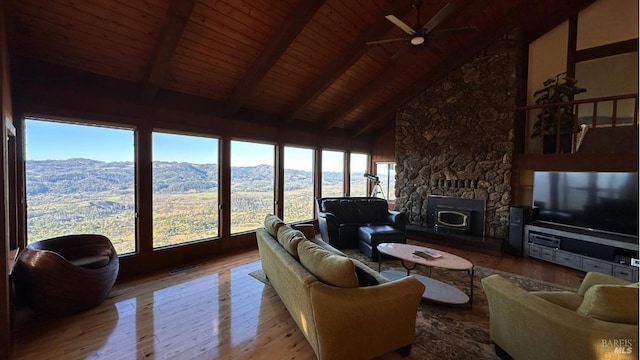 living area with a stone fireplace, wood finished floors, visible vents, wood ceiling, and beam ceiling