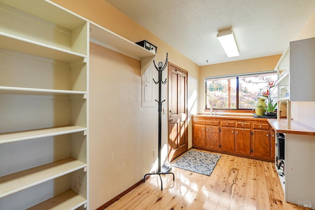 interior space featuring brown cabinets, open shelves, light countertops, light wood-style flooring, and a textured ceiling