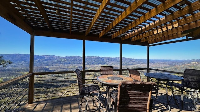 wooden deck with outdoor dining space, a mountain view, and a pergola