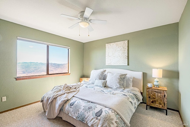 carpeted bedroom with a ceiling fan, a textured wall, and baseboards