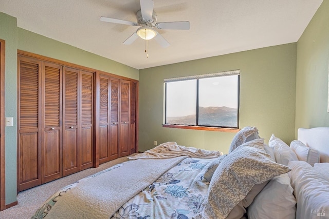 bedroom featuring light carpet, ceiling fan, and two closets