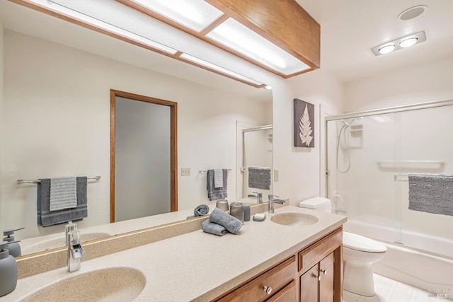 bathroom featuring bath / shower combo with glass door, a sink, toilet, and double vanity