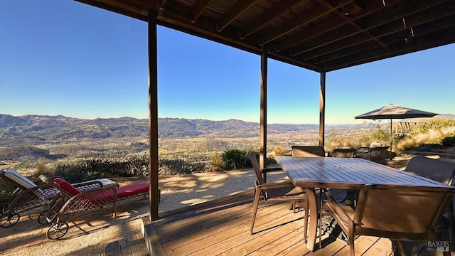 wooden terrace featuring outdoor dining space and a mountain view