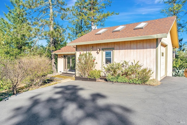 view of front of property with aphalt driveway, roof with shingles, and an attached garage