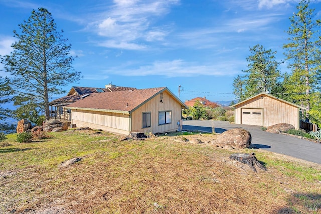 view of side of home featuring a yard, a detached garage, and an outbuilding