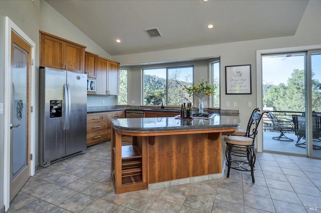 kitchen with plenty of natural light, a kitchen breakfast bar, lofted ceiling, and stainless steel appliances