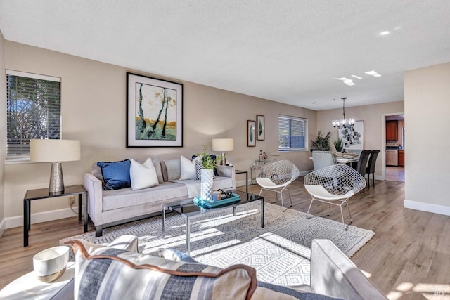 living room with plenty of natural light, a textured ceiling, light hardwood / wood-style flooring, and a notable chandelier