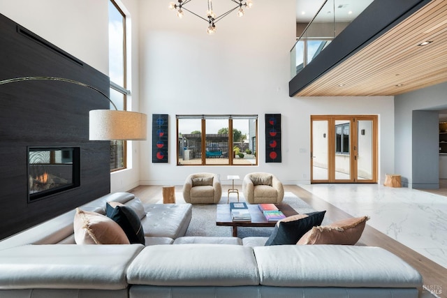 living room with a towering ceiling, a healthy amount of sunlight, and an inviting chandelier