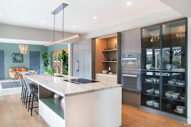 kitchen featuring pendant lighting, a large island, sink, gray cabinets, and stainless steel double oven