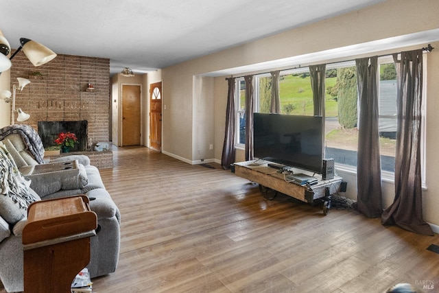 living room with wood-type flooring and a brick fireplace