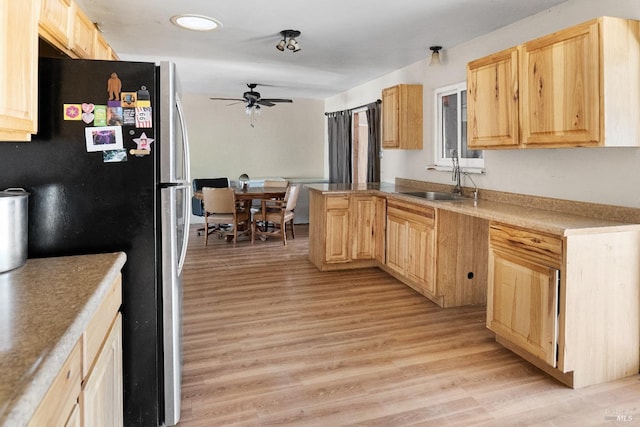 kitchen featuring light brown cabinetry, sink, stainless steel fridge, ceiling fan, and light hardwood / wood-style flooring