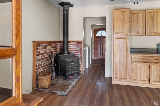 kitchen with light brown cabinets, dark wood-type flooring, and a wood stove