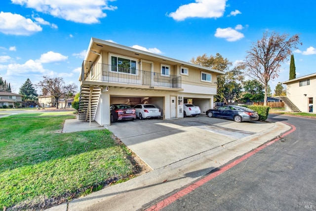 view of property featuring a garage, a balcony, and a front yard