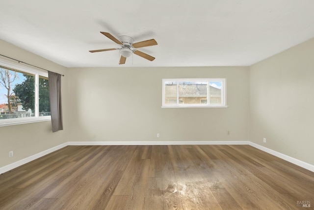 empty room featuring ceiling fan, plenty of natural light, and wood-type flooring