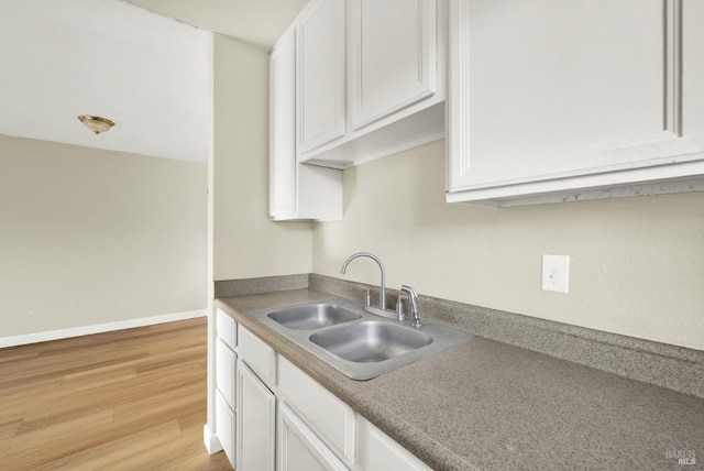 kitchen featuring white cabinetry, sink, and light hardwood / wood-style floors