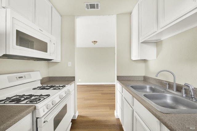 kitchen with white cabinetry, white appliances, sink, and hardwood / wood-style flooring