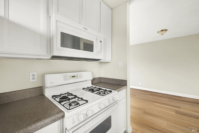 kitchen with white appliances, light wood-type flooring, and white cabinets