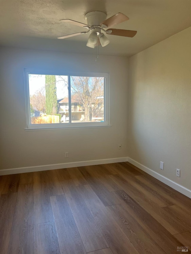 spare room featuring dark wood-type flooring and ceiling fan