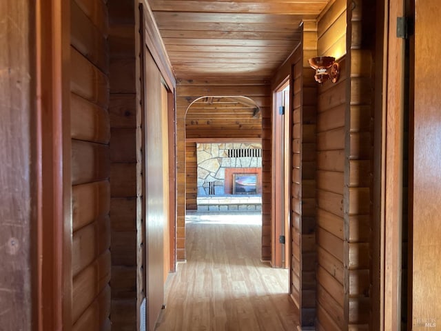 hallway featuring rustic walls, wood ceiling, and light wood-style flooring