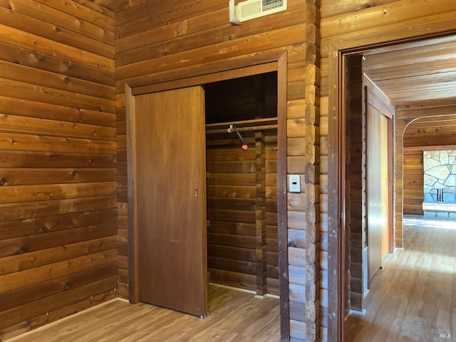 interior space with wood finished floors, visible vents, and wooden walls