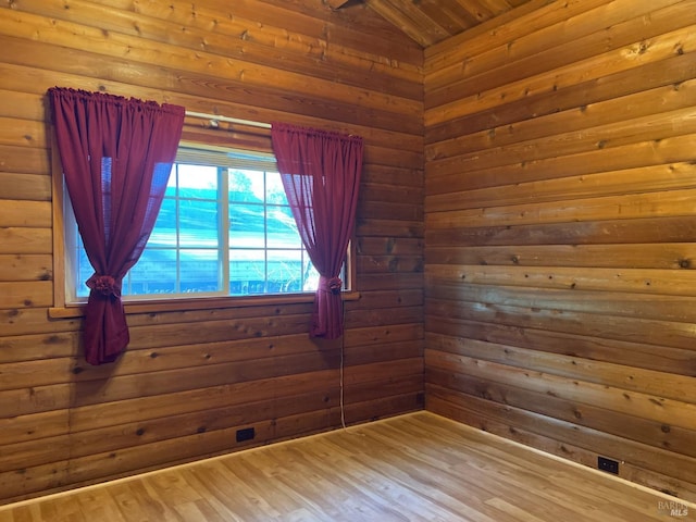 empty room featuring wooden ceiling, hardwood / wood-style floors, lofted ceiling, and wooden walls