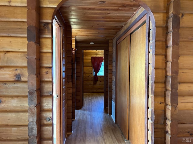 hallway with wooden ceiling, dark hardwood / wood-style flooring, and log walls