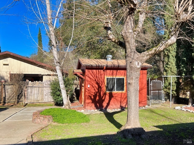 view of property exterior featuring an outdoor structure, a lawn, a storage shed, and fence