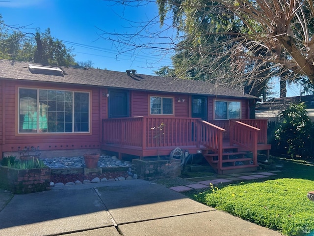 view of front of home with a wooden deck, a patio, and a front yard