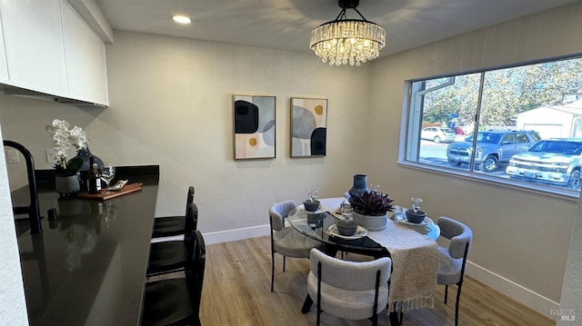 dining area with a notable chandelier and light hardwood / wood-style flooring