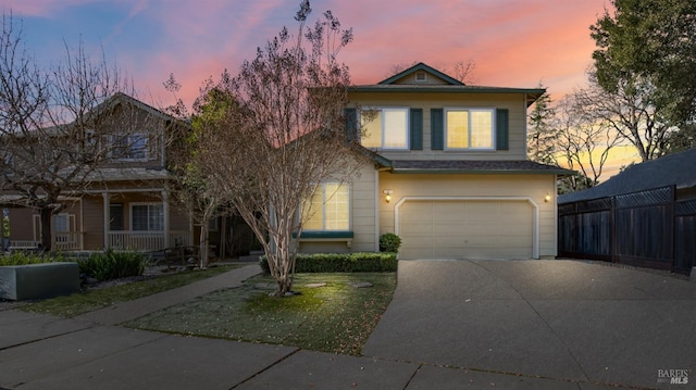 traditional home featuring covered porch, driveway, an attached garage, and fence