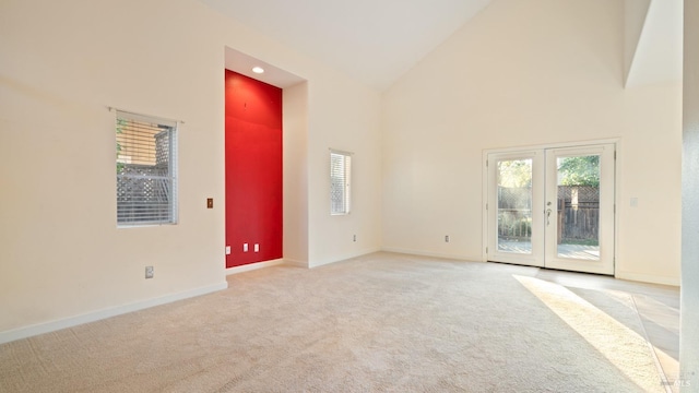 empty room featuring high vaulted ceiling, french doors, carpet flooring, and baseboards