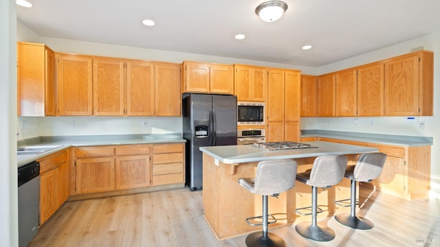 kitchen featuring appliances with stainless steel finishes, light wood-type flooring, a breakfast bar, and a center island