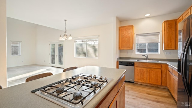 kitchen with light wood finished floors, decorative light fixtures, a sink, stainless steel appliances, and a notable chandelier