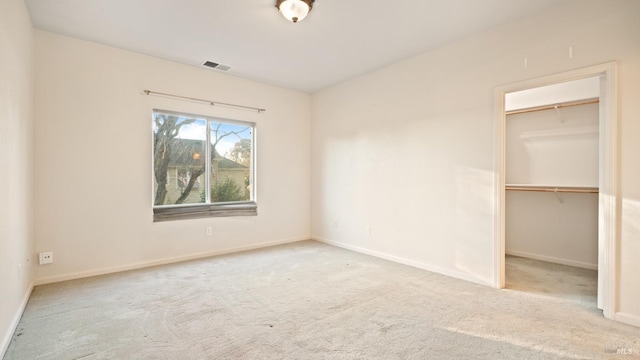 unfurnished bedroom with carpet, visible vents, a walk in closet, and baseboards