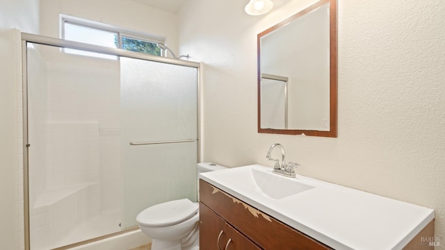 bathroom featuring a textured wall, vanity, an enclosed shower, and toilet