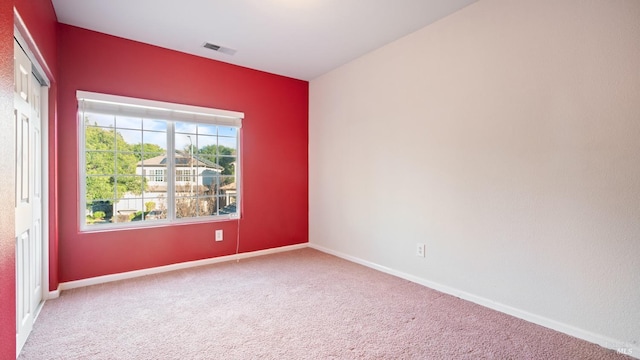 empty room featuring carpet, visible vents, and baseboards