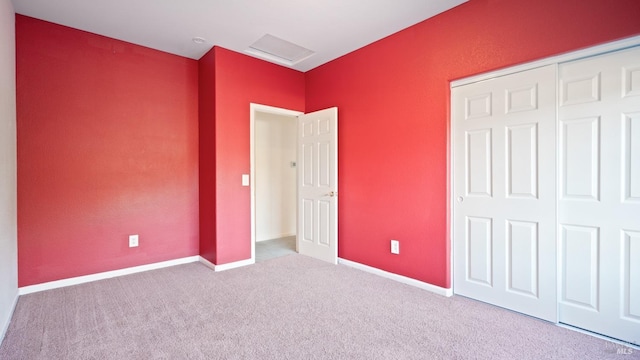 unfurnished bedroom with carpet floors, attic access, a closet, and baseboards