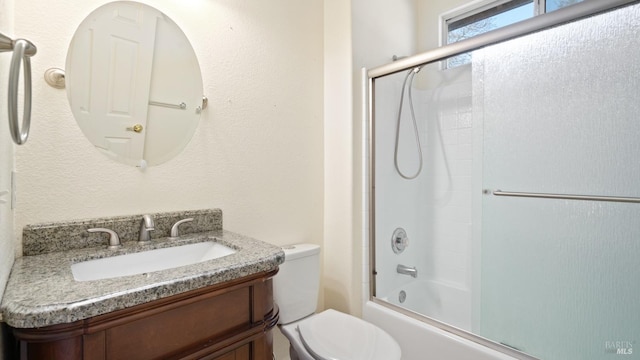 full bath with enclosed tub / shower combo, vanity, and toilet