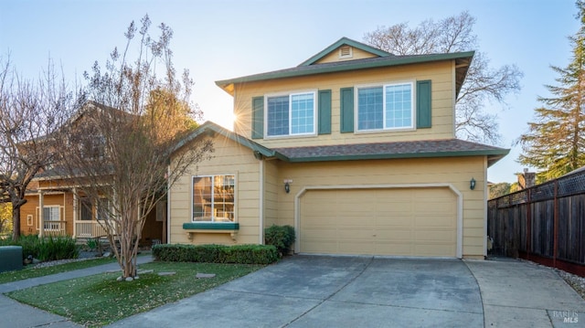 traditional-style home with driveway, an attached garage, and fence