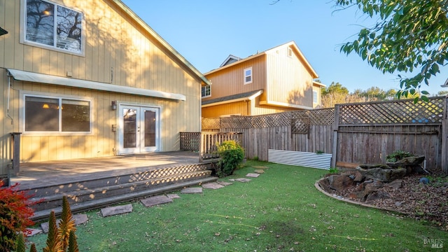 rear view of house with french doors, fence, a wooden deck, and a lawn