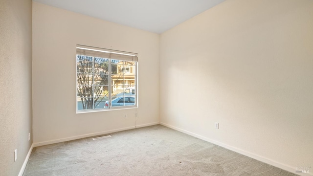 empty room featuring carpet, visible vents, and baseboards