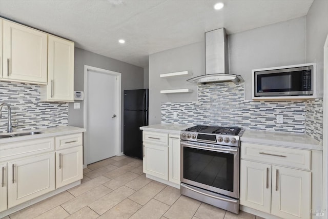 kitchen featuring appliances with stainless steel finishes, tasteful backsplash, white cabinetry, sink, and wall chimney exhaust hood