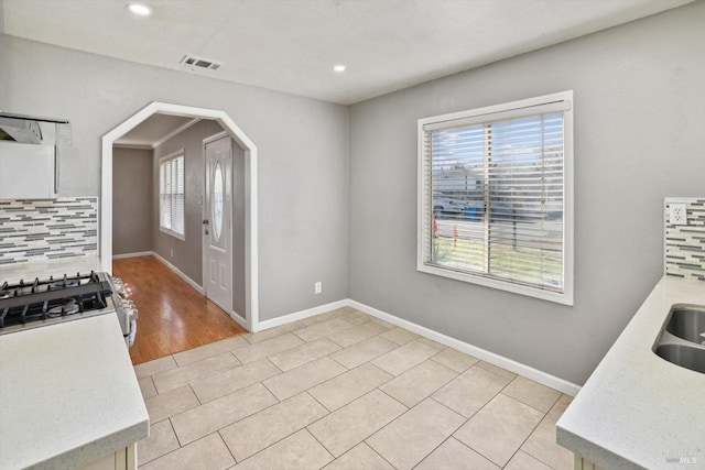 kitchen with light tile patterned flooring, stainless steel gas range, and tasteful backsplash