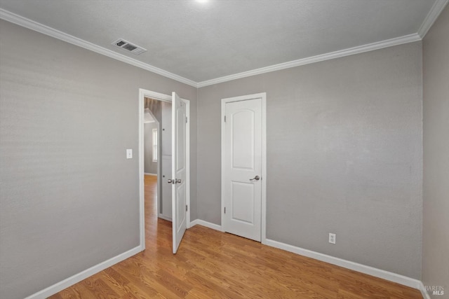 empty room with light hardwood / wood-style flooring and ornamental molding