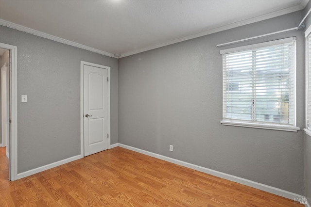 empty room featuring ornamental molding and light wood-type flooring