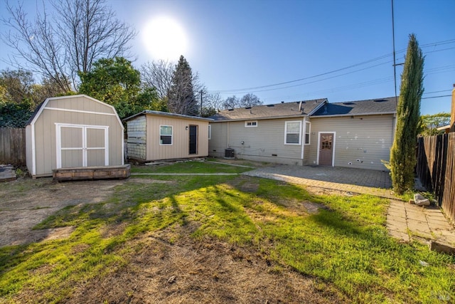 rear view of house featuring cooling unit, a patio, a shed, and a lawn