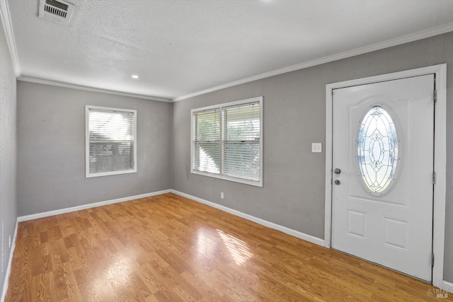 entrance foyer with light hardwood / wood-style floors, plenty of natural light, and crown molding