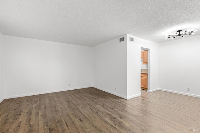 empty room with wood-type flooring and a textured ceiling