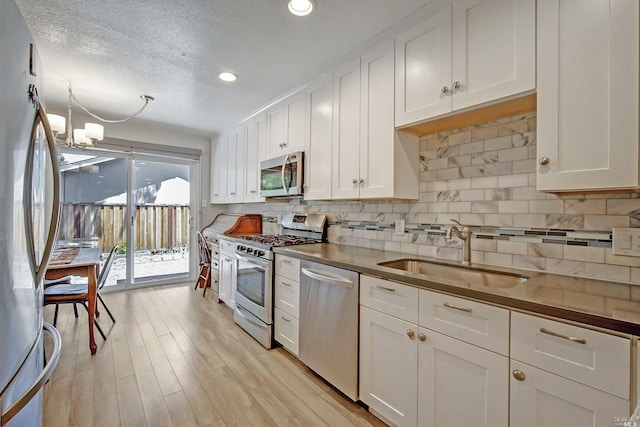 kitchen featuring a textured ceiling, tasteful backsplash, sink, white cabinets, and stainless steel appliances