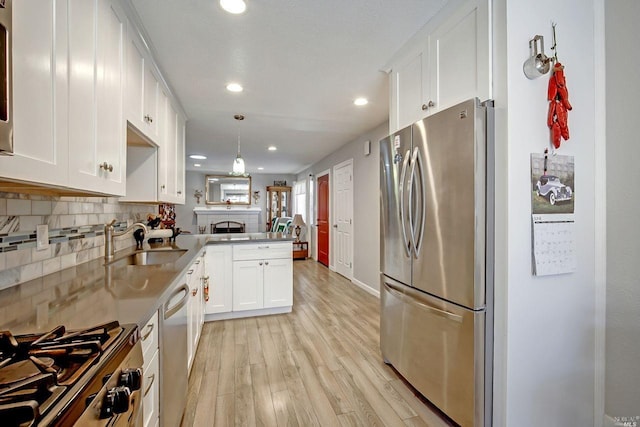 kitchen featuring kitchen peninsula, hanging light fixtures, sink, white cabinets, and stainless steel appliances